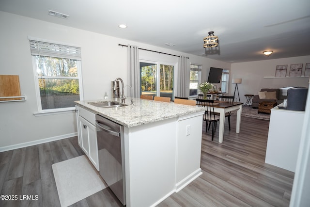 kitchen with dishwasher, an island with sink, sink, white cabinets, and hardwood / wood-style flooring