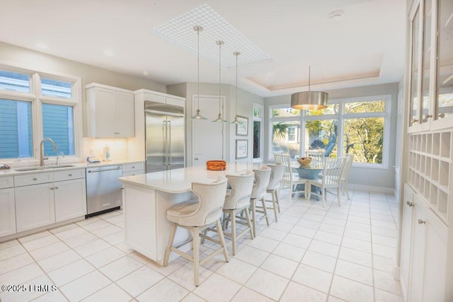 kitchen featuring pendant lighting, sink, stainless steel appliances, white cabinets, and a kitchen island