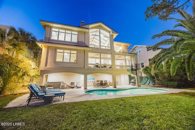 back of house featuring a patio, a balcony, a lawn, and a pool with hot tub