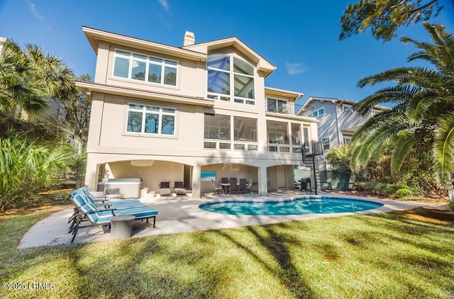 rear view of property featuring area for grilling, a sunroom, a patio area, and a lawn