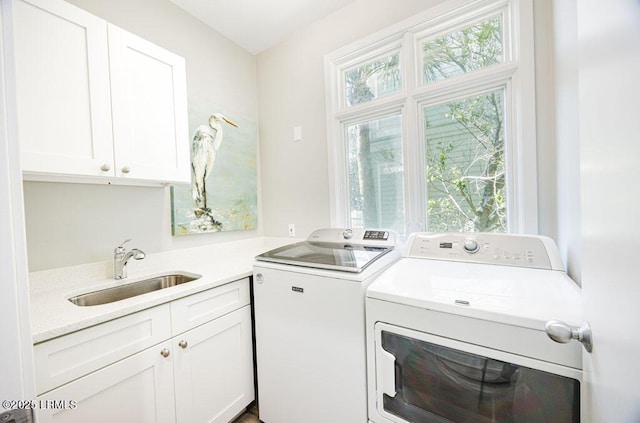 laundry area with sink, washing machine and dryer, and cabinets