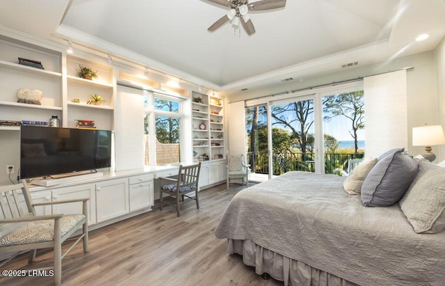 bedroom with ceiling fan, ornamental molding, light hardwood / wood-style floors, access to outside, and a raised ceiling