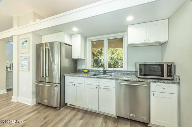 kitchen featuring appliances with stainless steel finishes, stone countertops, sink, and white cabinets