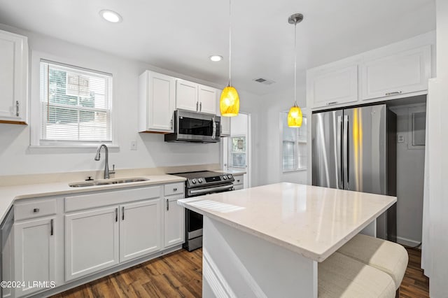 kitchen featuring sink, white cabinetry, appliances with stainless steel finishes, a kitchen island, and pendant lighting