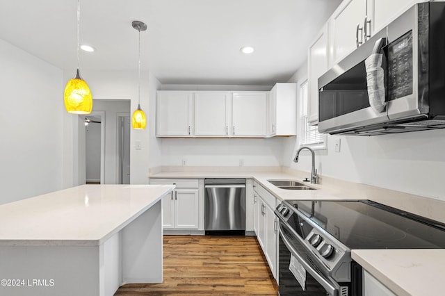 kitchen with sink, light hardwood / wood-style flooring, appliances with stainless steel finishes, white cabinetry, and hanging light fixtures