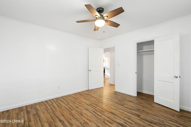 unfurnished bedroom with ornamental molding, dark wood-type flooring, ceiling fan, and a closet