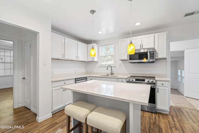 kitchen featuring appliances with stainless steel finishes, hanging light fixtures, and white cabinets