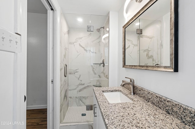 bathroom with walk in shower, vanity, and hardwood / wood-style flooring