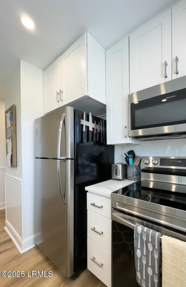 kitchen with light countertops, light wood-style flooring, white cabinetry, and stainless steel appliances