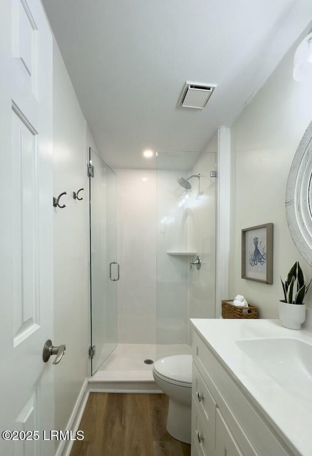 full bath featuring vanity, a stall shower, toilet, visible vents, and wood finished floors