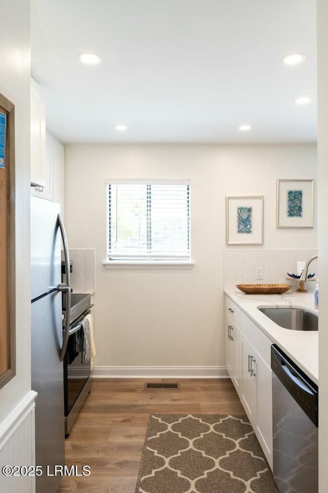 kitchen with light wood-style flooring, white cabinets, visible vents, a sink, and stainless steel appliances