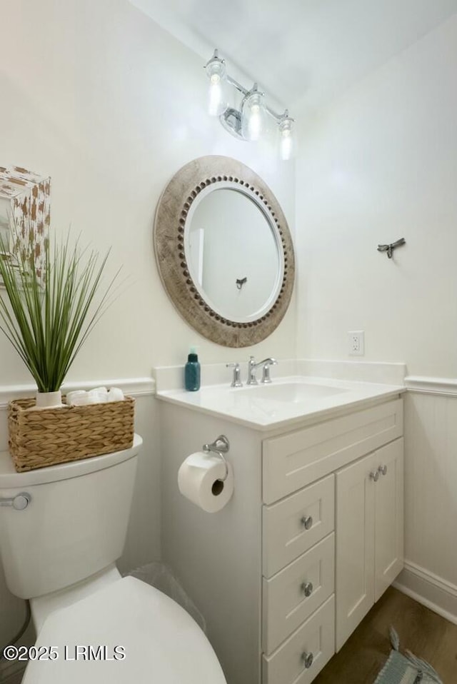 half bathroom featuring vanity, toilet, and wood finished floors