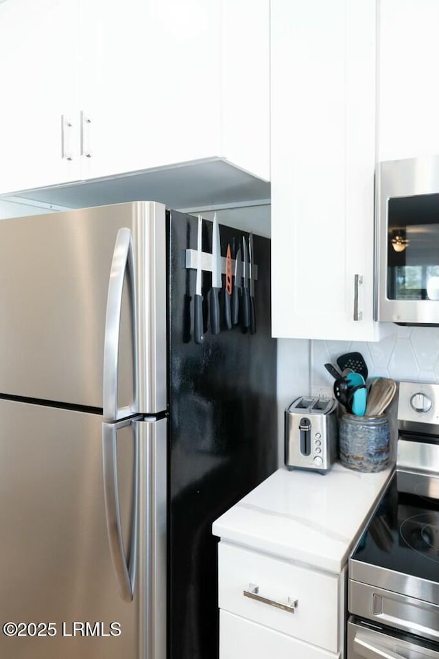kitchen with white cabinetry, light countertops, backsplash, and appliances with stainless steel finishes