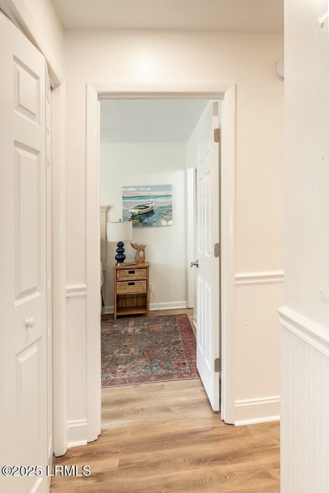 hall with baseboards and light wood finished floors