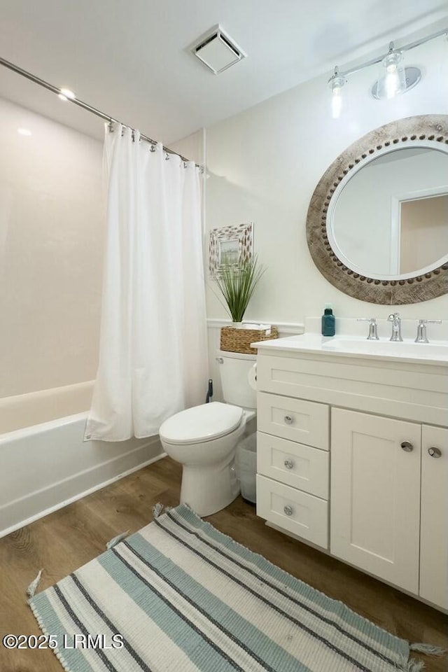 full bath with visible vents, shower / bath combination with curtain, toilet, vanity, and wood finished floors