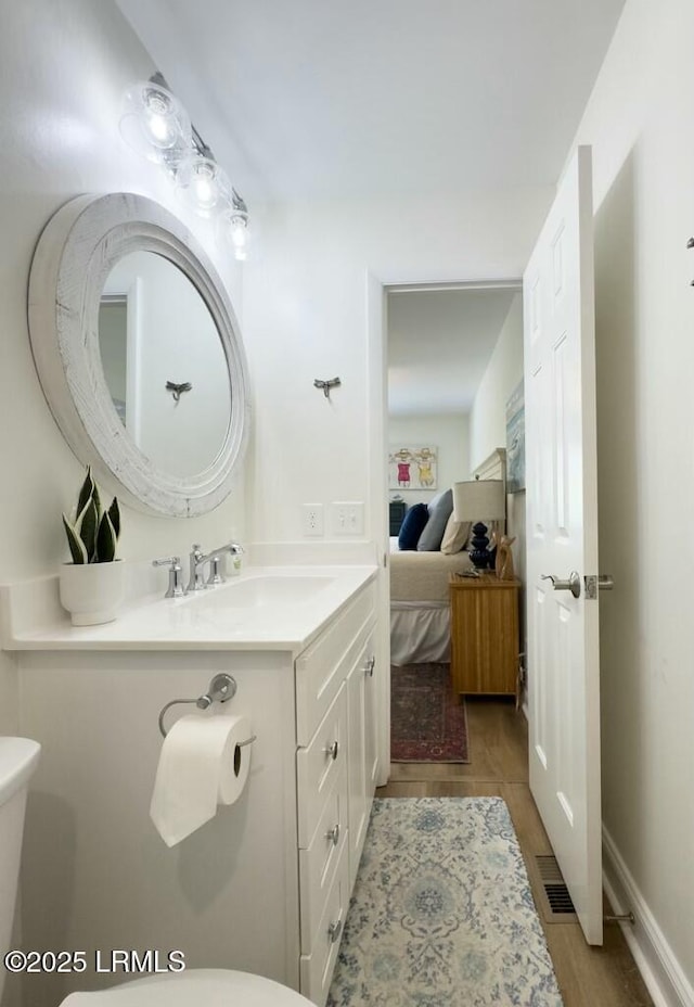 ensuite bathroom with ensuite bath, vanity, visible vents, and toilet