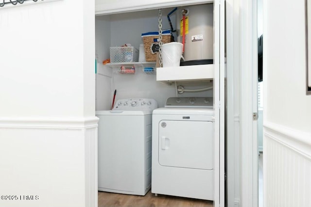 clothes washing area with light wood-style floors, wainscoting, independent washer and dryer, and laundry area