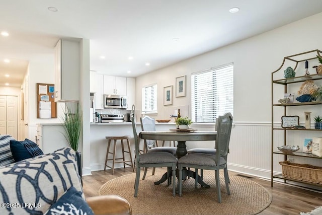 dining room featuring wood finished floors, a wainscoted wall, and recessed lighting