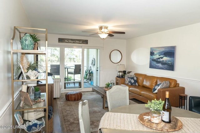 carpeted living room featuring a ceiling fan and wainscoting