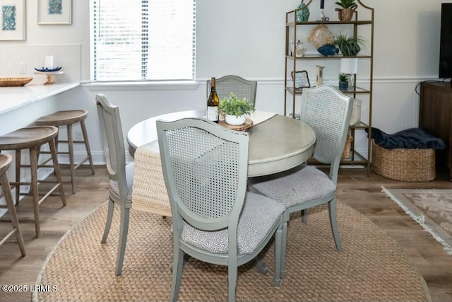 dining area with wainscoting and wood finished floors