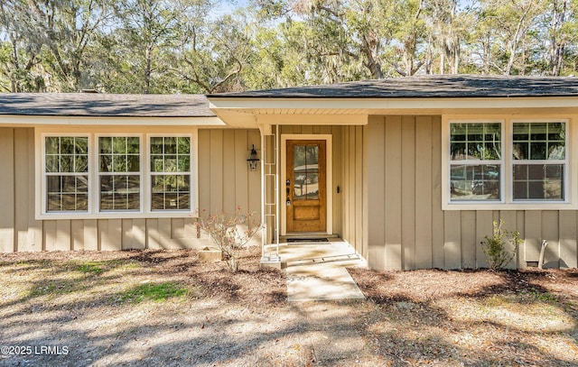 entrance to property featuring board and batten siding and roof with shingles