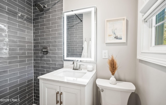 full bath featuring toilet, a tile shower, and vanity