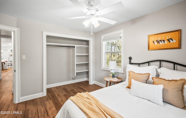 bedroom featuring dark wood-type flooring, a closet, baseboards, and a ceiling fan