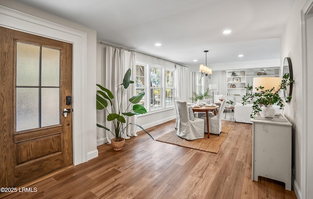 dining area with light wood finished floors, baseboards, a notable chandelier, and recessed lighting