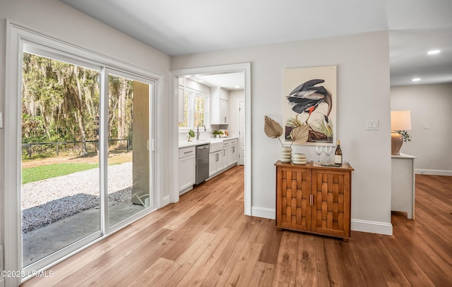 entryway featuring light wood-style flooring, baseboards, a sink, and recessed lighting