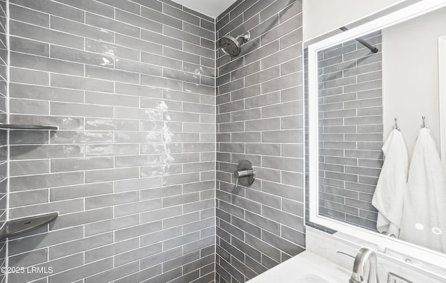 full bath featuring a tile shower and a sink