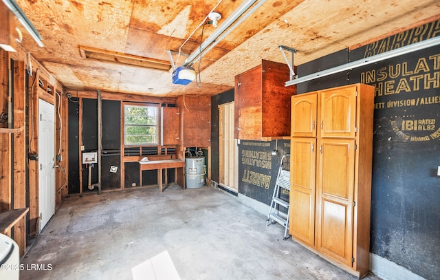 misc room with a garage, water heater, and concrete flooring