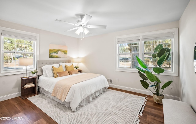 bedroom with dark wood-style floors, visible vents, ceiling fan, and baseboards