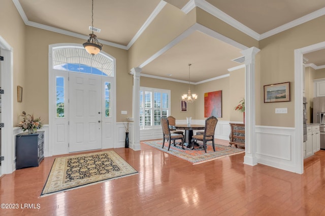 foyer with decorative columns, crown molding, and light hardwood / wood-style flooring