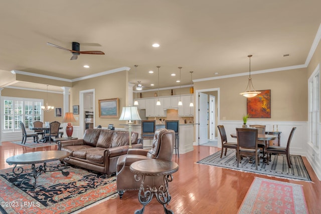 living room with crown molding, light wood-type flooring, and ceiling fan