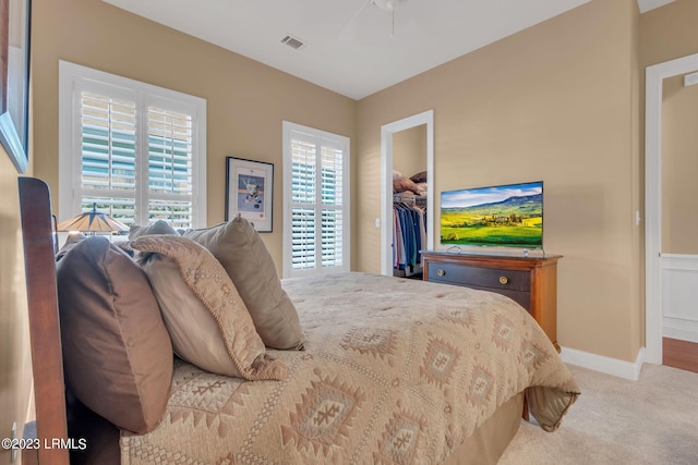 bedroom with multiple windows, a walk in closet, a closet, and carpet