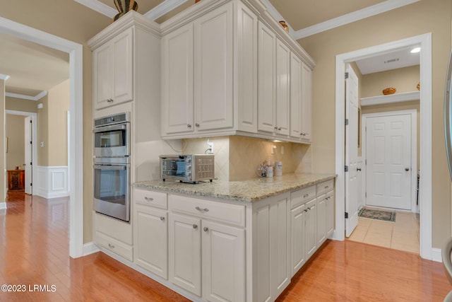 kitchen featuring white cabinetry, double oven, light stone counters, and backsplash