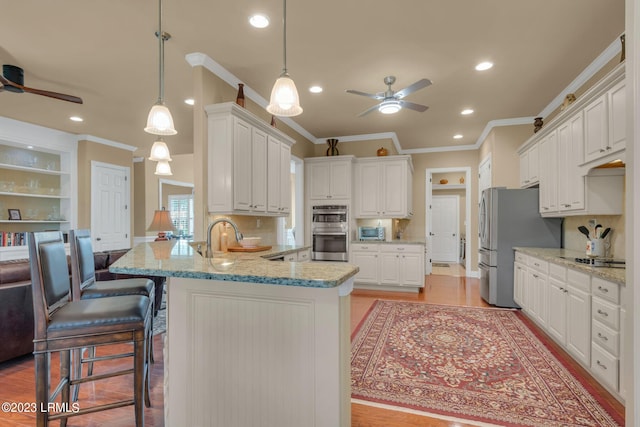 kitchen featuring appliances with stainless steel finishes, hanging light fixtures, tasteful backsplash, white cabinets, and kitchen peninsula