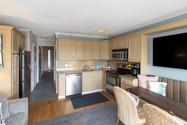 kitchen featuring dark wood-type flooring, sink, crown molding, stainless steel appliances, and decorative backsplash