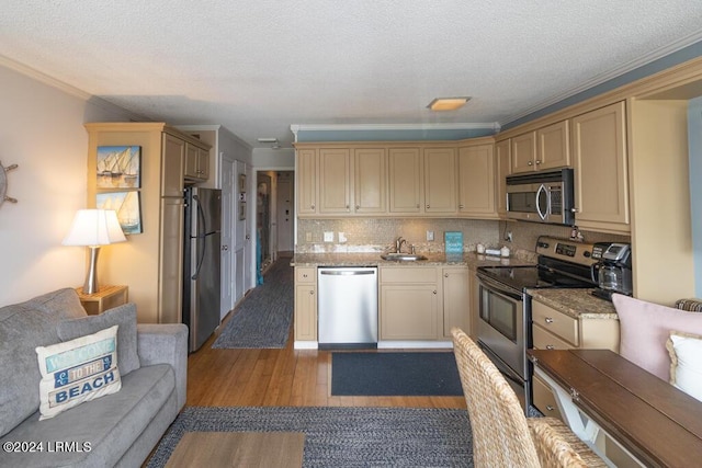 kitchen featuring sink, decorative backsplash, ornamental molding, light hardwood / wood-style floors, and stainless steel appliances