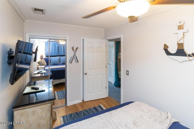 bedroom with hardwood / wood-style floors, ornamental molding, and ceiling fan