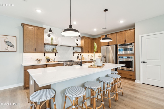 kitchen with brown cabinets, light wood-style flooring, stainless steel appliances, premium range hood, and tasteful backsplash
