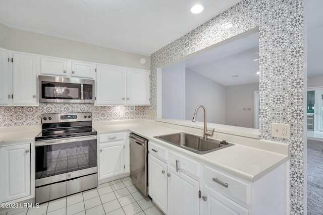 kitchen with light tile patterned floors, stainless steel appliances, light countertops, white cabinetry, and a sink