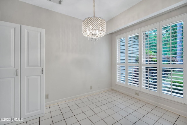 spare room featuring baseboards, light tile patterned flooring, and an inviting chandelier