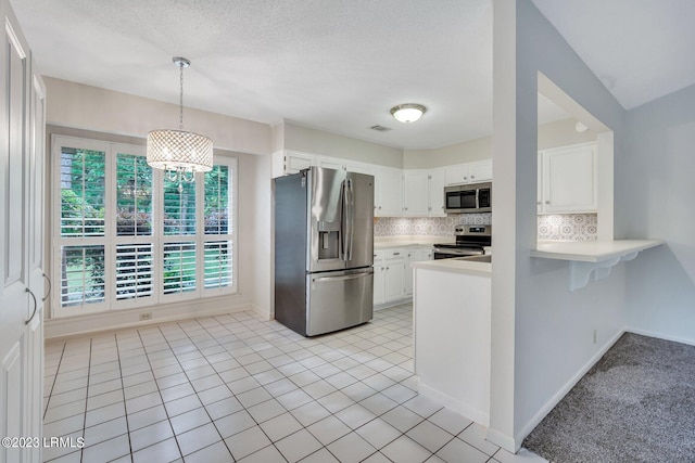 kitchen featuring light tile patterned floors, stainless steel appliances, light countertops, white cabinetry, and backsplash