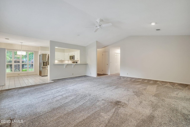 unfurnished living room with vaulted ceiling, ceiling fan with notable chandelier, visible vents, and light colored carpet