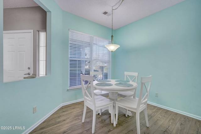 dining area featuring visible vents, a textured ceiling, baseboards, and wood finished floors