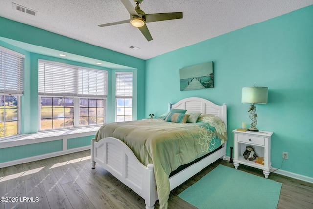 bedroom featuring visible vents, a textured ceiling, and wood finished floors