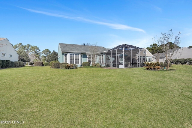 rear view of property with glass enclosure and a yard