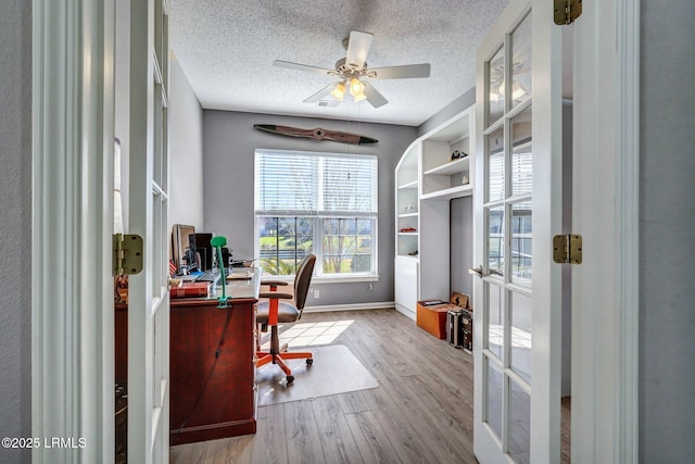 office with french doors, light wood-style floors, ceiling fan, a textured ceiling, and baseboards