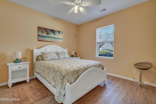 bedroom with visible vents, ceiling fan, baseboards, and wood finished floors